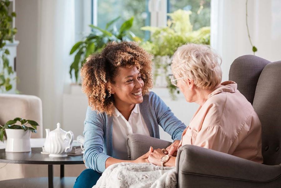 Lady and resident smiling and talking in a home lounge