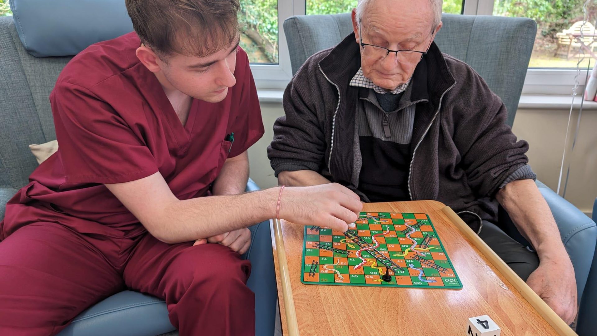 Elderly man and carer playing snakes and ladders